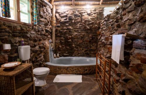 a stone bathroom with a tub and a toilet at Pioneer Camp in Lusaka