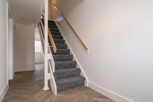 a staircase in a home with white walls and wood floors at Willow retreat in Royal Tunbridge Wells