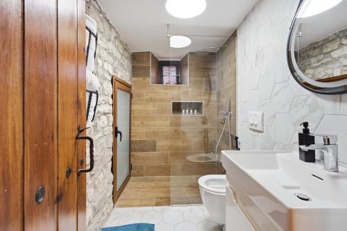 a bathroom with a sink and a toilet and a mirror at Villa Kokoshi, an extraordinary experience. in Berat