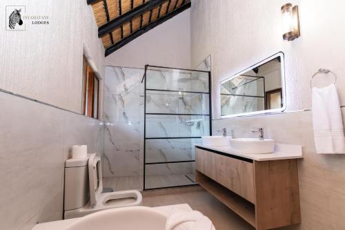 a bathroom with a toilet and a sink and a shower at INYAMATANE LUXURY LODGES at Kruger Park Lodge in Hazyview