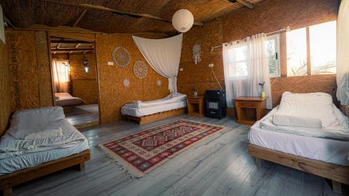 a bedroom with two beds and a rug at Zman Midbar Eco Spirit Lodge for Peace in Arad