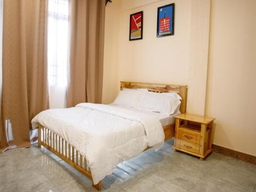 a bedroom with a bed and a nightstand next to a window at Kili Tanzania in Moshi