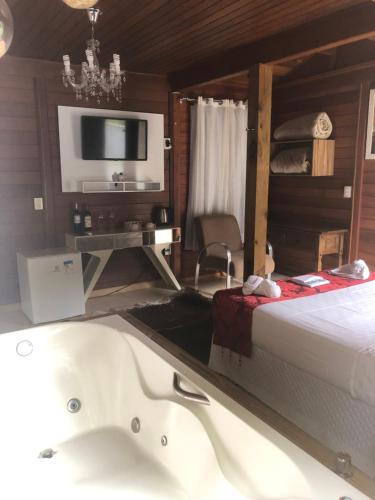 a bedroom with a tub and a bed and a tv at Pousada requinte serrano in Urubici