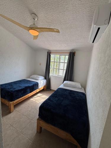 ein Schlafzimmer mit zwei Betten und einem Fenster in der Unterkunft Casa Cayo in Ixtapa