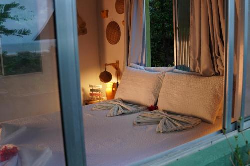 a bedroom with a bed with pillows and a window at Casa de Mar - Praia do Sagi in Baía Formosa