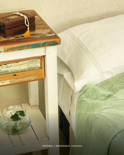 a side table with a glass bowl on a bed at INDIRA Hospedaje Canning in Canning