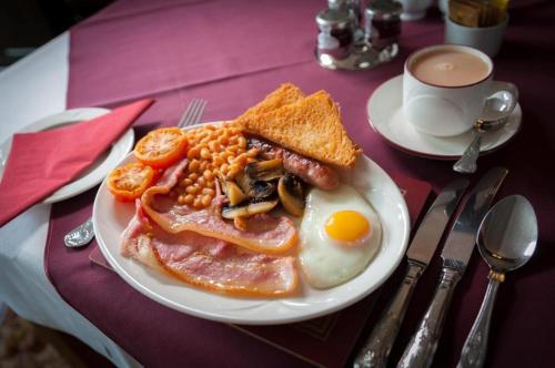 a plate of breakfast food on a table with a cup of coffee at Potters Mooring Guest House in Teignmouth