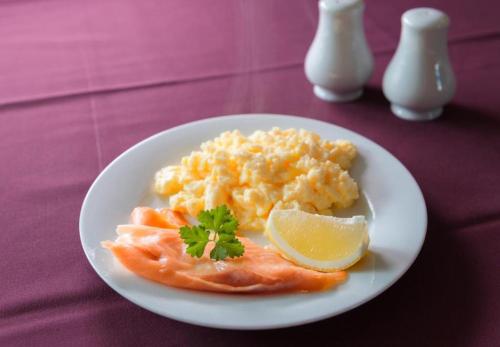 a plate of food with salmon and a wedge of lemon at Potters Mooring Guest House in Teignmouth