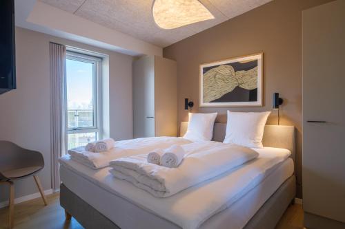 a bedroom with a large white bed with towels on it at Aalborg Hotel Apartments in Aalborg