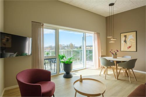 a living room with a table and chairs and a large window at Aalborg Hotel Apartments in Aalborg