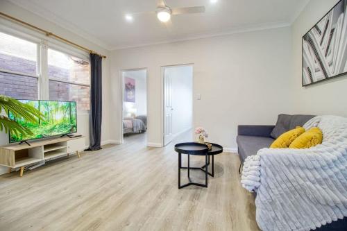 a living room with a couch and a flat screen tv at Coastal & Connected Summer Resort Parking in Cronulla