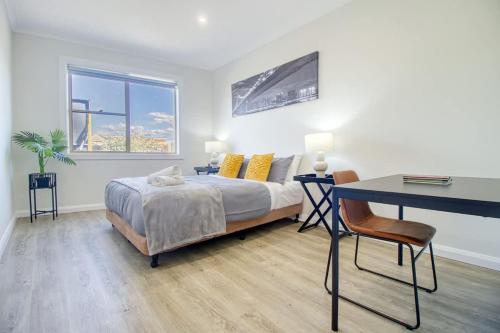 a bedroom with a bed and a desk and a table and chair at Coastal & Connected Summer Resort Parking in Cronulla