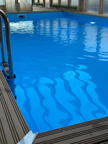 a swimming pool with blue water at Domki Złote Piaski Kryty Basen Sauna Jacuzzi in Jastrzębia Góra