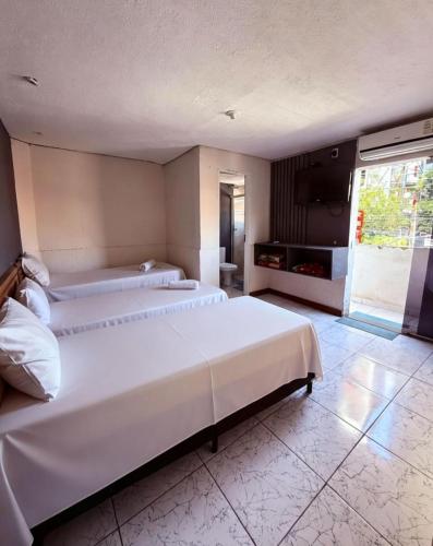 a large bedroom with two beds and a television at Hotel Nações Unidas in São Paulo