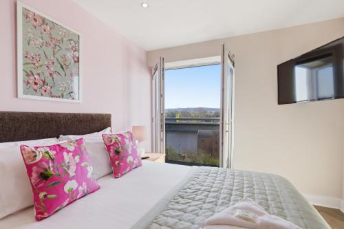 a bedroom with a white bed with pink pillows and a window at High Quays Apartments - Properties Unique in Newcastle upon Tyne