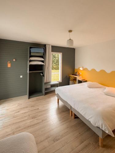a bedroom with a bed and a desk and a window at Hôtel Les Voisins Beaucemaine in Ploufragan