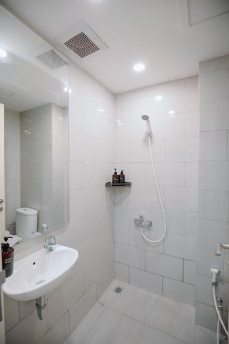 a white bathroom with a shower and a sink at Lavy at Anderson Pakuwon Mall in Surabaya