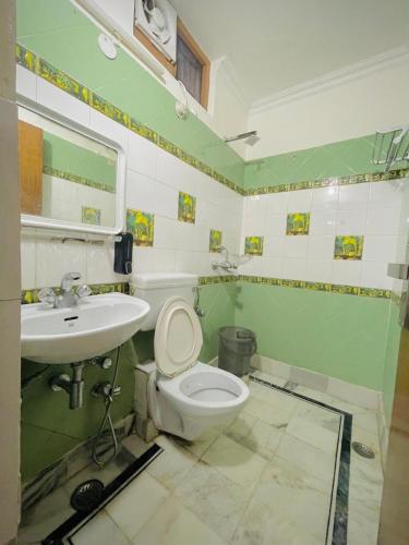 a green and white bathroom with a toilet and a sink at Hotel Har Ki Pauri with terrace Ganga view in Haridwār