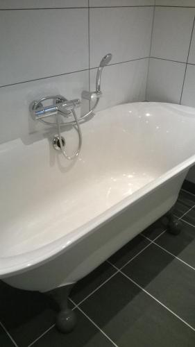 a white bath tub with a faucet in a bathroom at Carpe Diem in Ommen