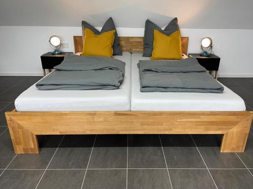 a wooden bed with yellow pillows on top of it at Modernes Apartment in Haiger Allendorf in Haiger