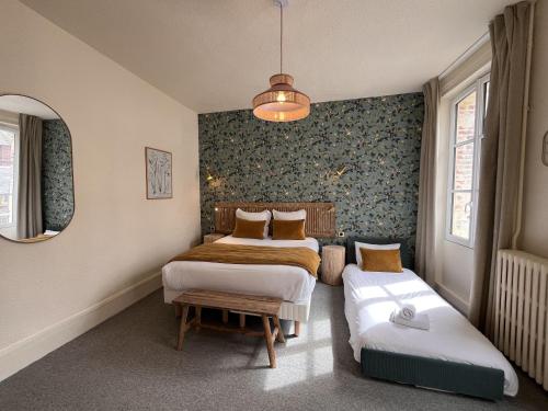 a bedroom with two beds and a bench in it at Le Trouville - Hôtel de Charme in Trouville-sur-Mer