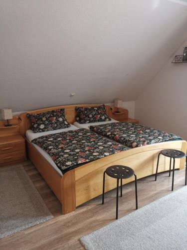 a bedroom with a large bed with two stools at Ferienwohnung am Dörenberg in Georgsmarienhütte