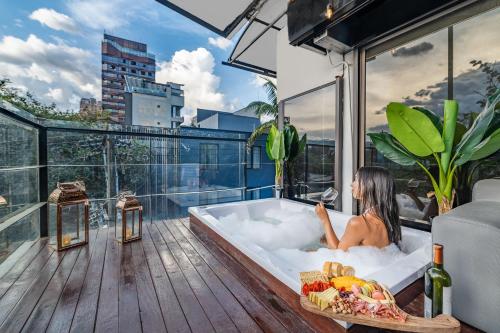 a woman sitting in a bath tub on a balcony at Ultimate 9BR Lleras Villa W Heated Pool in Medellín