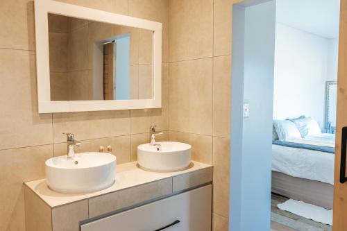two sinks in a bathroom with a bed and a mirror at New Wave Accommodation in George