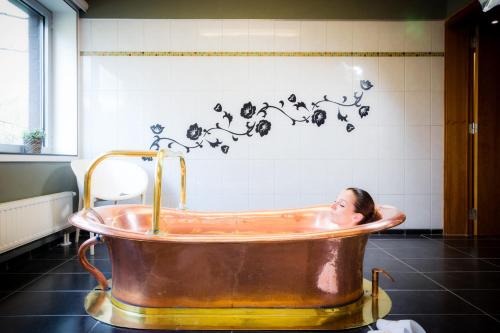 a woman sitting in a copper tub in a bathroom at Table Rase chambres d'hôtes, restaurant et weekend aux Thermes de Spa in Theux