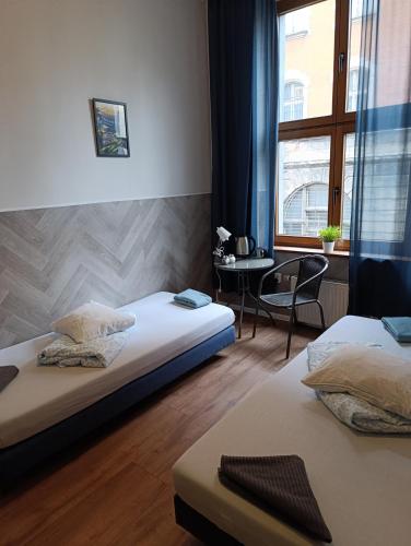 a bedroom with two beds and a table and a window at Hostel Kamienica Rynek 7 in Katowice