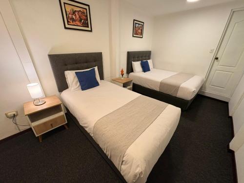 a hotel room with two beds and a night stand at Hotel Altara AQP in Arequipa