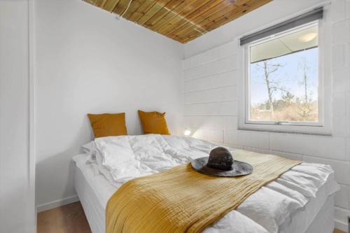 a bedroom with a bed with a hat on it at 84307-8400-Skovduevej-4 in Fuglslev