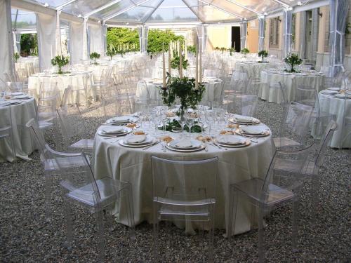 a room filled with tables and chairs with white linens at Sina Villa Matilde in Romano Canavese
