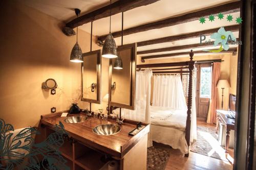 a bathroom with two sinks and a bedroom at Hotel Ruralis Peña Del Alba in Arroyomolinos de la Vera