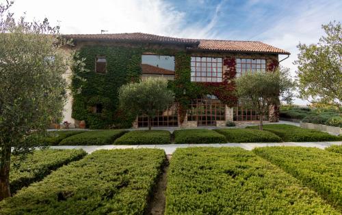 a house covered in ivy with bushes and trees at Relais dei Poderi Einaudi in Dogliani