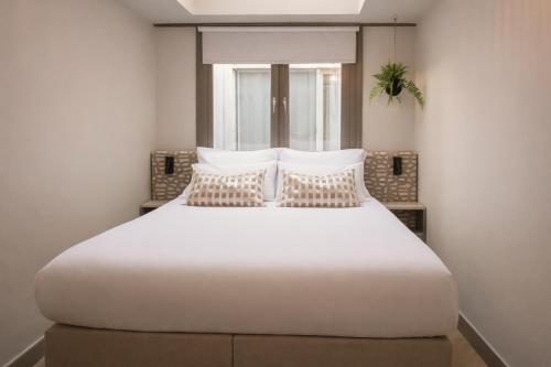 a large white bed with pillows and a window at Hotel Central Staytion in Amsterdam