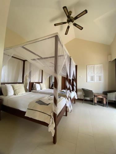 a bedroom with a canopy bed and a ceiling fan at Mandharini UNIT 35 in Kilifi
