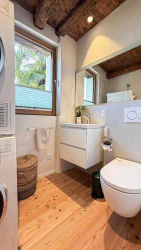 a bathroom with a toilet and a sink and a window at Cavigliano Rustico - free parking in Cavigliano
