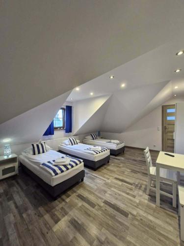 three beds in a room with a table and chairs at Pokoje u Emilii in Mikołajki