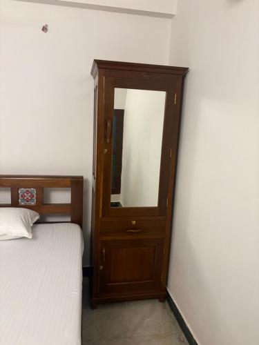 a wooden cabinet with a mirror next to a bed at Rainbow721 Earth in Pondicherry