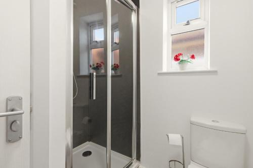 a bathroom with a shower with a toilet and a window at 4BR with Private Parking in Wyken