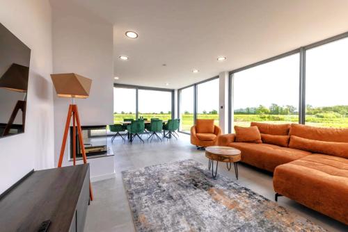 a living room with orange furniture and large windows at Villa Aurora mit Sauna und Whirlpool in Dranske