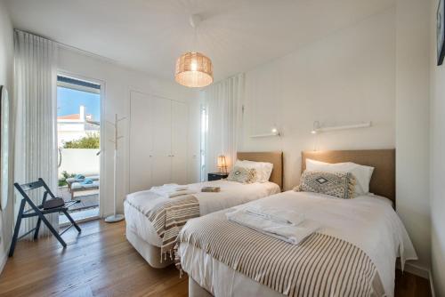 two beds in a white room with a window at Casas do Forte by MY CHOICE in Tavira