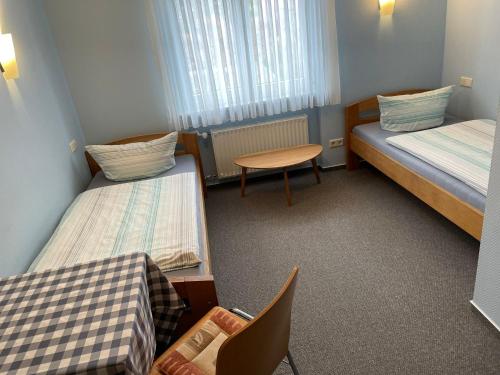 a room with two beds and a table and a chair at Hotel Garni Pension Ruth in Mutterstadt
