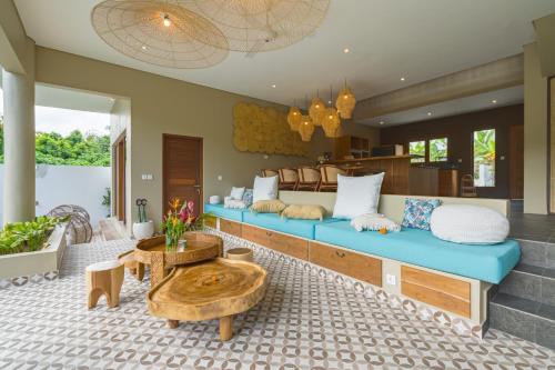 a living room with a blue couch and a table at Villa Canopy - Spacious Luxury 4BR Villa Near Nuanu and Luna Beach Club in Tabanan
