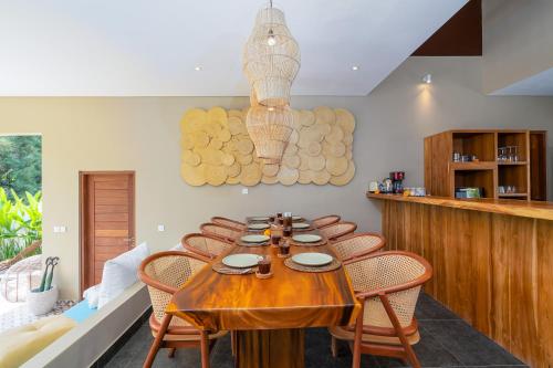 a dining room with a wooden table and chairs at Villa Canopy - Spacious Luxury 4BR Villa Near Nuanu and Luna Beach Club in Tabanan