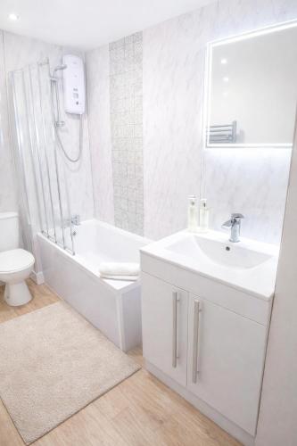 a bathroom with a sink and a tub and a toilet at Cosy Alnwick Apartment in Alnwick