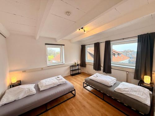 two beds in a room with two windows at Spektakuläres Turm-Loft mit Aussicht in Braunschweig