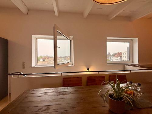 a dining room with two windows and a wooden table at Spektakuläres Turm-Loft mit Aussicht in Braunschweig