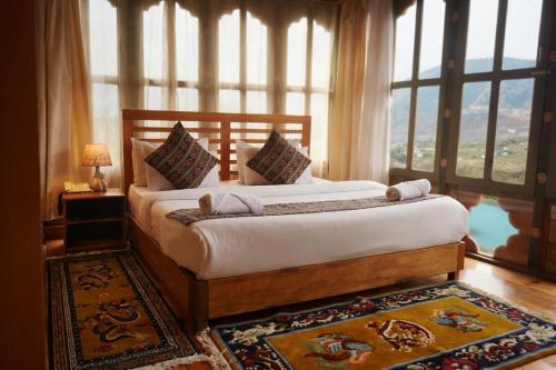 a bedroom with a large bed with a large window at Kingaling Hotel in Punākha